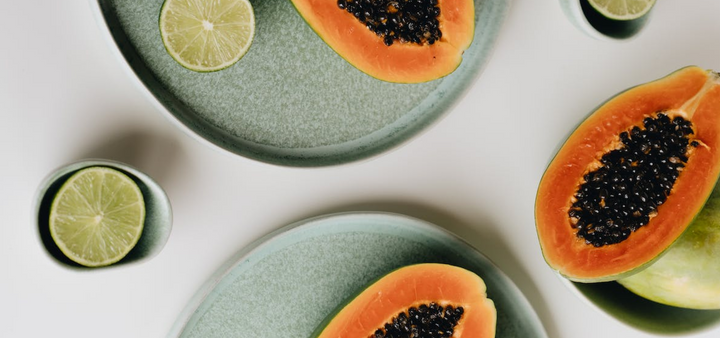 Papaya and limes on dishes on a white surface