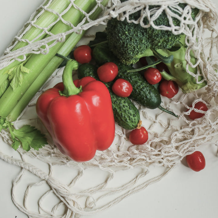 A net grocery bag filled with fresh vegetables