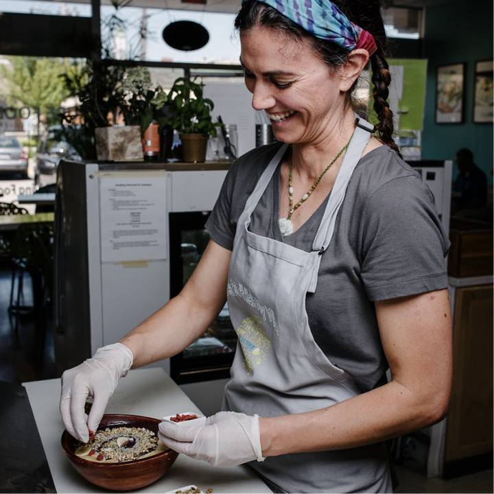 A Pure Juice Cafe employee assembles as acai bowl